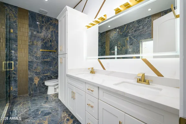 a bathroom with a granite countertop sink a toilet and shower