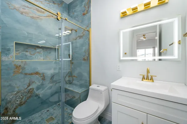 a bathroom with a toilet sink vanity and shower