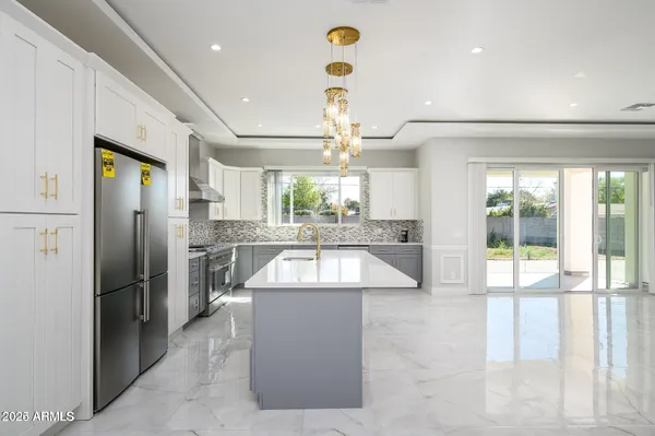 a large kitchen with stainless steel appliances kitchen island granite countertop a refrigerator and a sink
