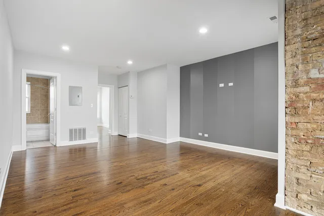 a view of an empty room with wooden floor and closet