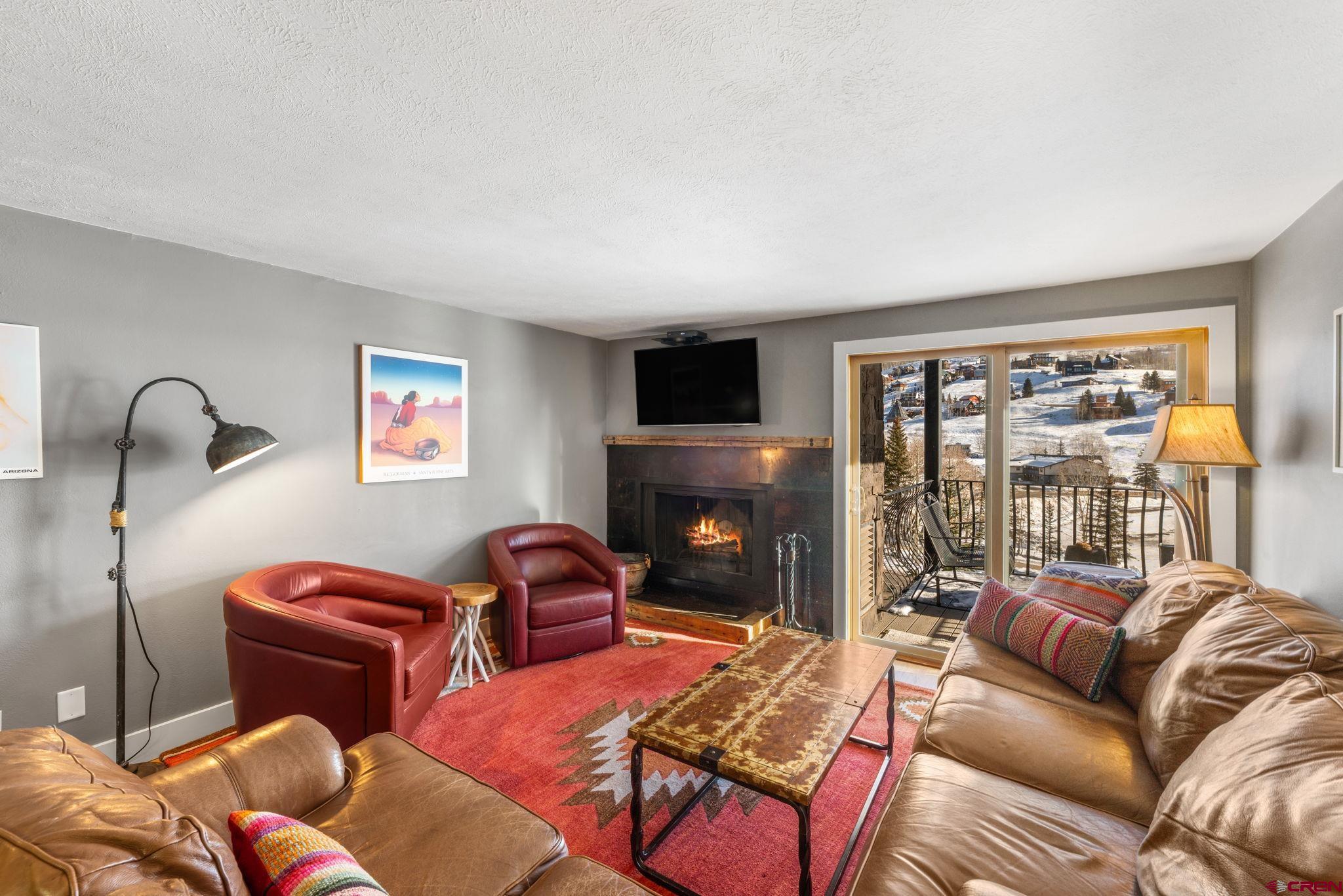 651 Gothic Road, Unit 505 Crested Butte, CO 81225 - Photo 25 of 44 a living room with furniture a fireplace and a flat screen tv