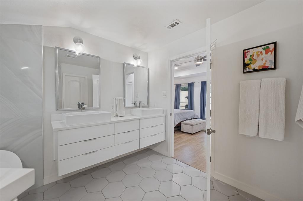 3619 Merrell Road Dallas, TX 75229 - Photo 22 of 26 Modern bathroom featuring a floating dual vanity with vessel sinks, wall-mounted light fixtures, and large hexagonal floor tiles
