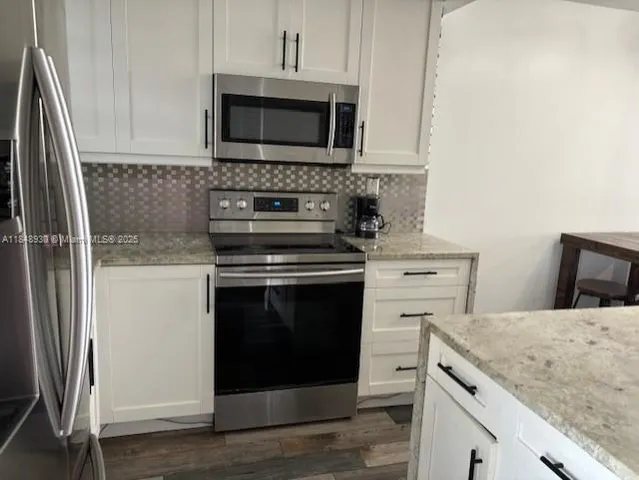 a kitchen with white cabinets and stainless steel appliances