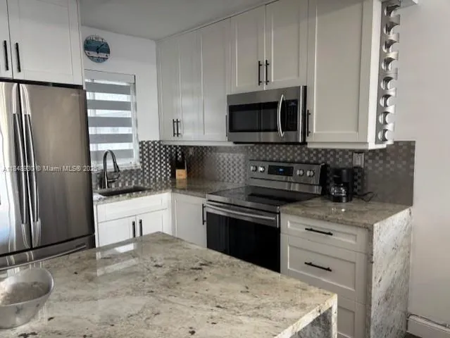 a kitchen with stainless steel appliances granite countertop a stove a refrigerator and a sink