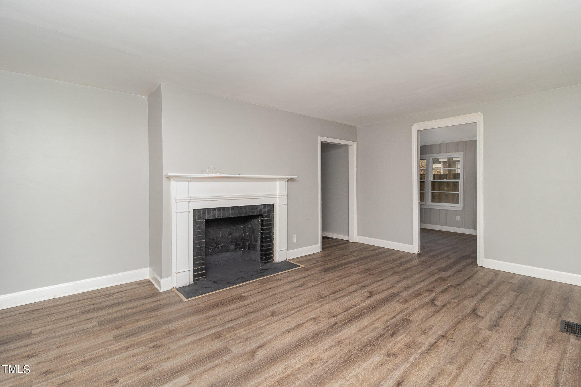 2813 Fowler Avenue Raleigh, NC 27607 - Photo 6 of 30 a view of an empty room with wooden floor fireplace and a window