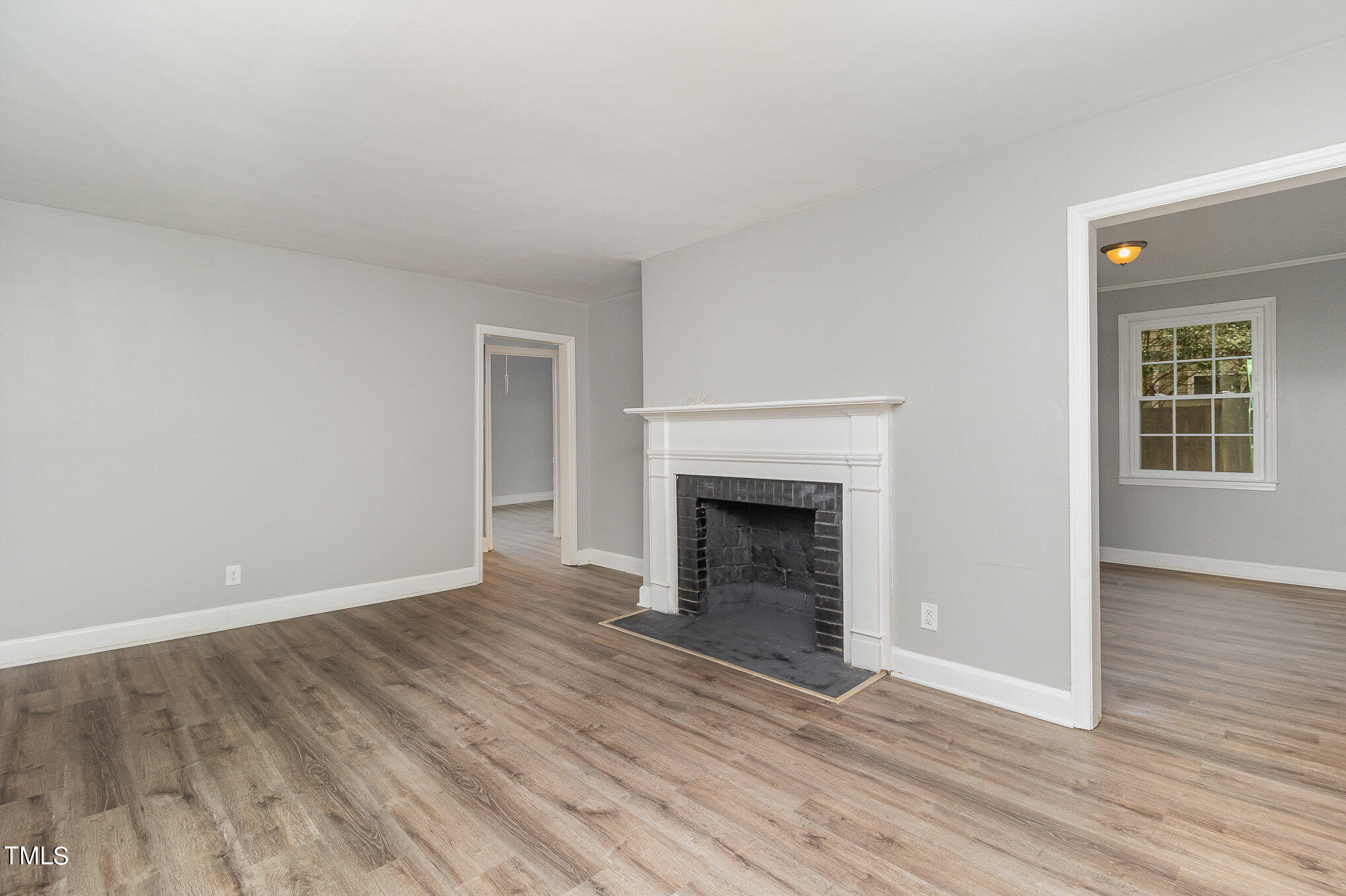 2813 Fowler Avenue Raleigh, NC 27607 - Photo 8 of 30 a view of an empty room with wooden floor fireplace and a window