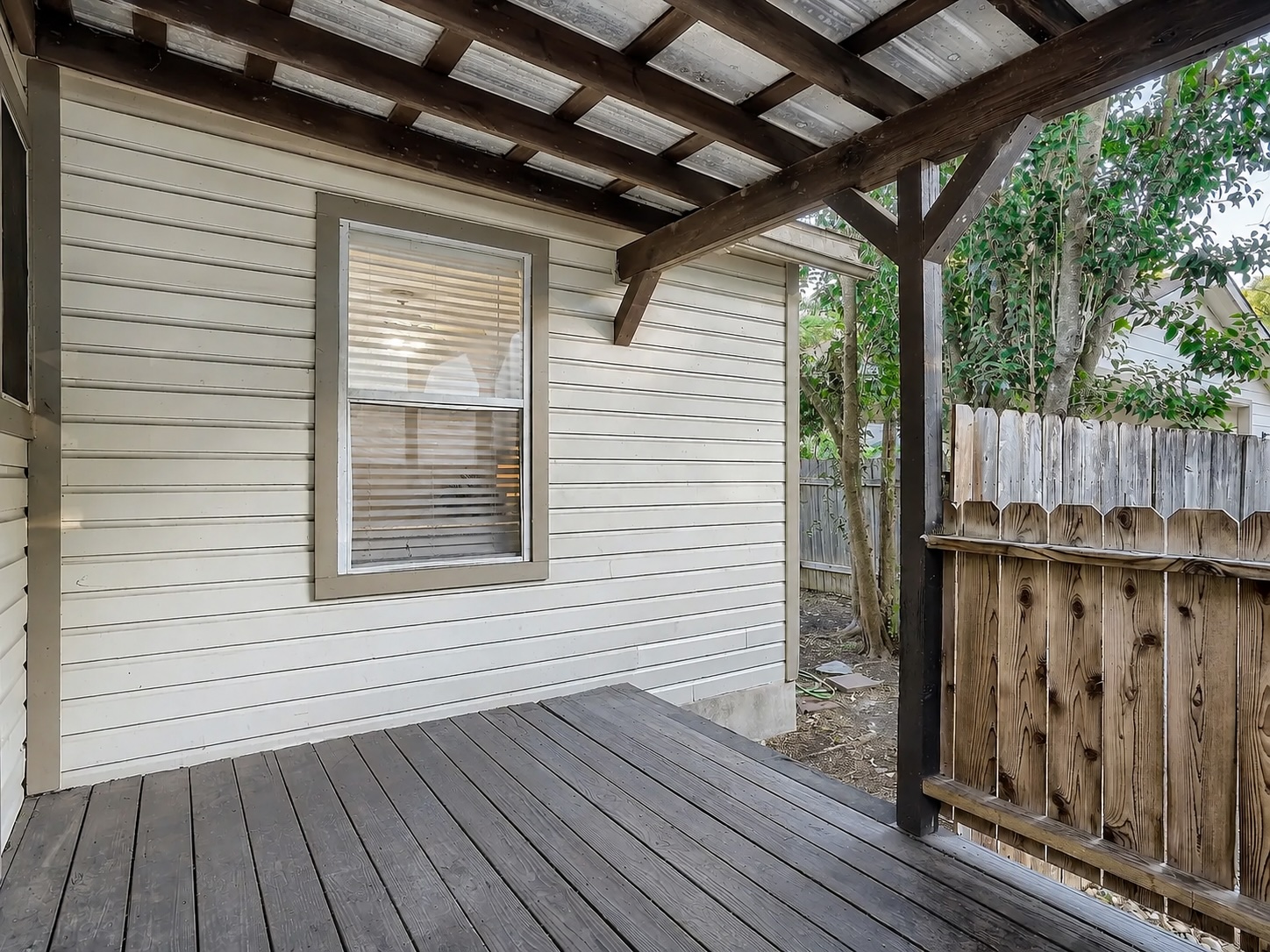 2009 Richcreek Road Austin, TX 78757 - Photo 15 of 23 A covered wooden deck features rustic overhead beams and adjacent fencing.