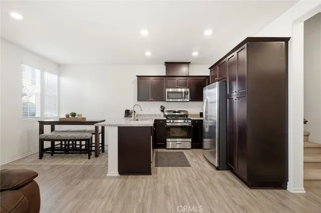 a kitchen with kitchen island wooden floors appliances and cabinets