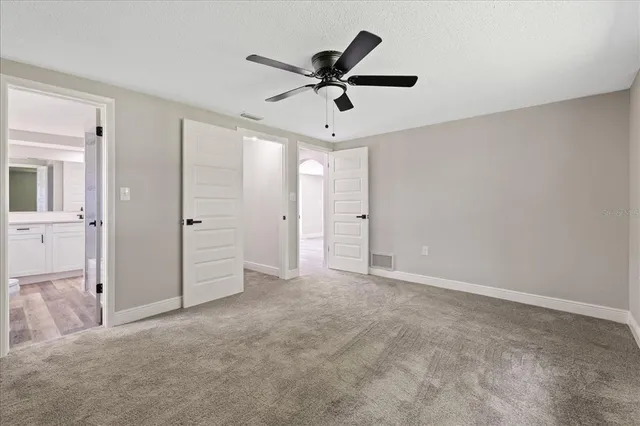 an empty room with closet and a ceiling fan