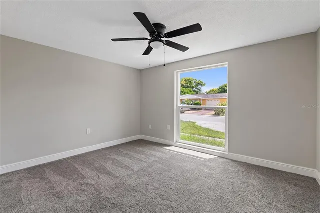 an empty room with ceiling fan and windows