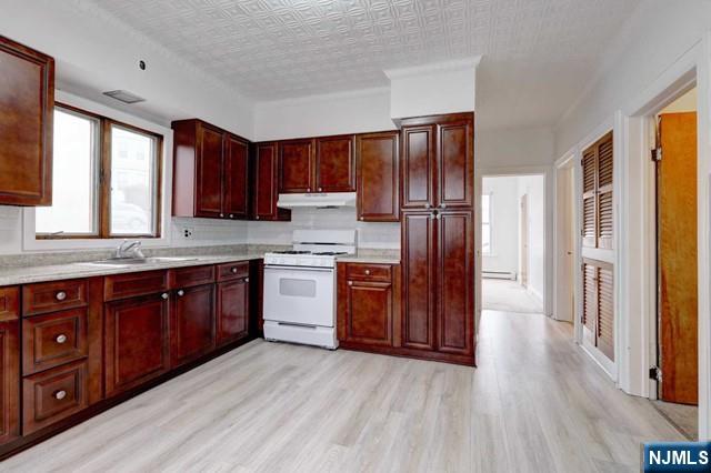 58 Westervelt Avenue, Unit 1 Hawthorne, NJ 07506 - Photo 1 of 17 a kitchen with stainless steel appliances granite countertop a refrigerator a sink dishwasher and wooden cabinets with wooden floor