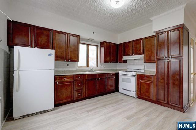 58 Westervelt Avenue, Unit 1 Hawthorne, NJ 07506 - Photo 2 of 17 a kitchen with stainless steel appliances granite countertop a refrigerator stove a sink dishwasher and wooden cabinets with wooden floor