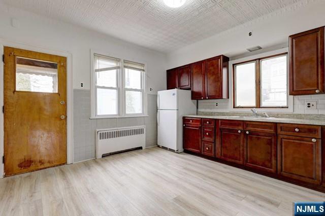 58 Westervelt Avenue, Unit 1 Hawthorne, NJ 07506 - Photo 4 of 17 a kitchen with granite countertop wooden cabinets and white appliances
