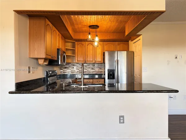 a kitchen with stainless steel appliances granite countertop a sink a stove and a refrigerator