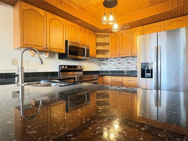 a kitchen with stainless steel appliances granite countertop a sink a stove and a refrigerator