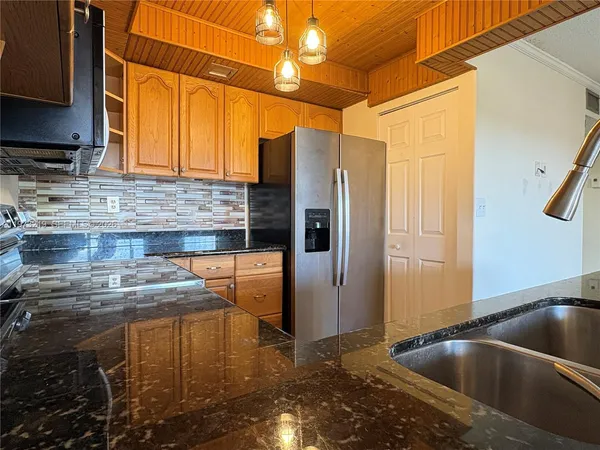 a kitchen with stainless steel appliances granite countertop a sink a refrigerator and a stove
