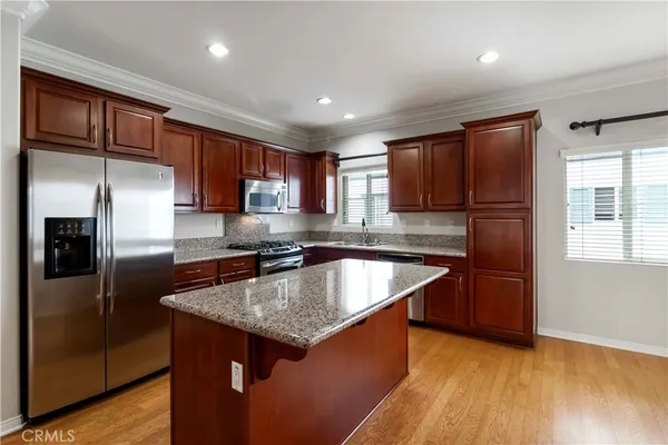 a kitchen with stainless steel appliances granite countertop a refrigerator a sink a stove a microwave and wooden cabinets