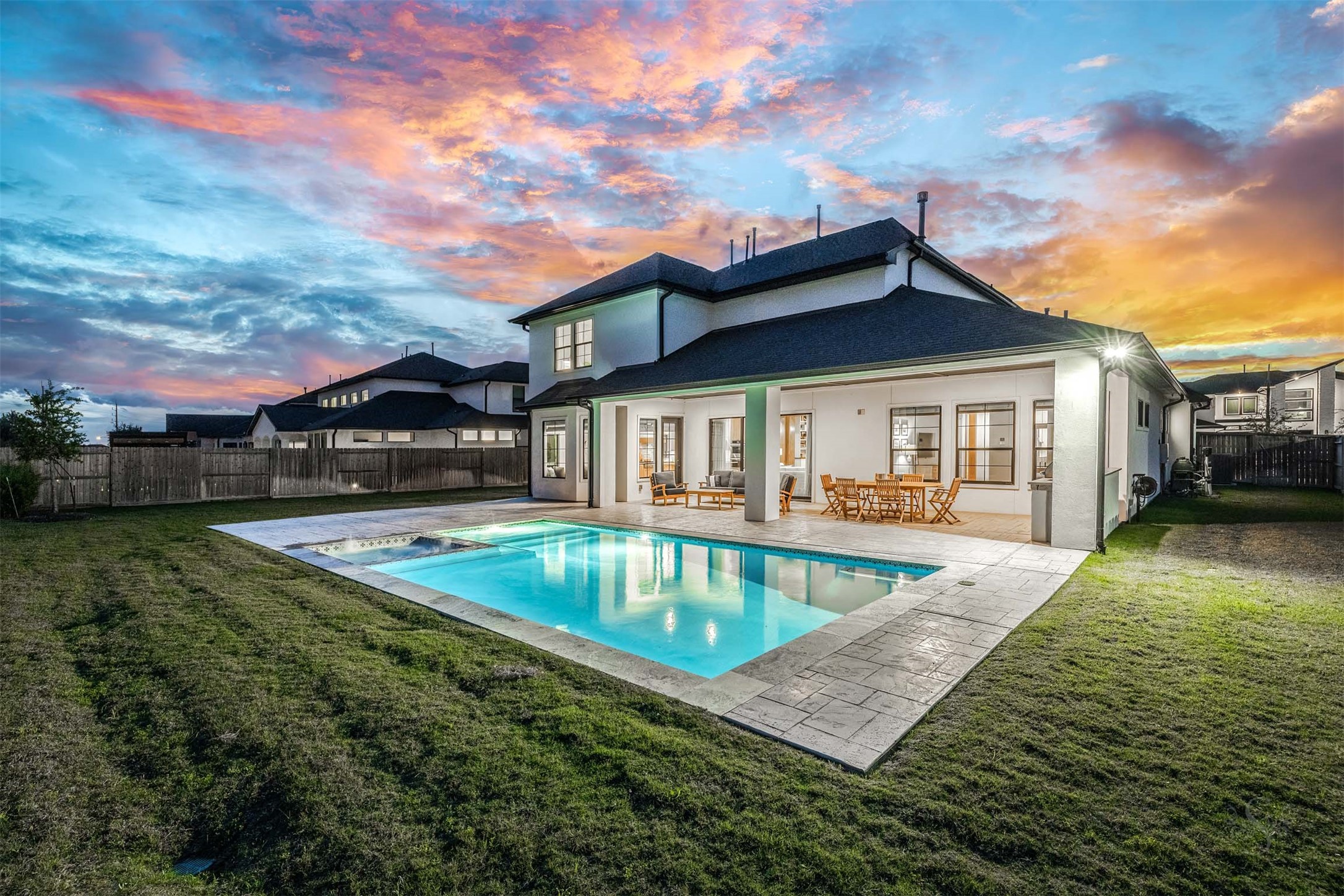 27919 Indigo Ridge Drive Fulshear, TX 77441 - Photo 43 of 50 The resort-style backyard offers a shimmering pool and spa surrounded by expansive stone decking, all set against a deep, manicured yard that provides ample room for play, pets, or future enhancements. An extended covered patio with outdoor kitchen elevates the space even further, creating a refined setting for alfresco dining, entertaining, and luxurious year-round outdoor living.