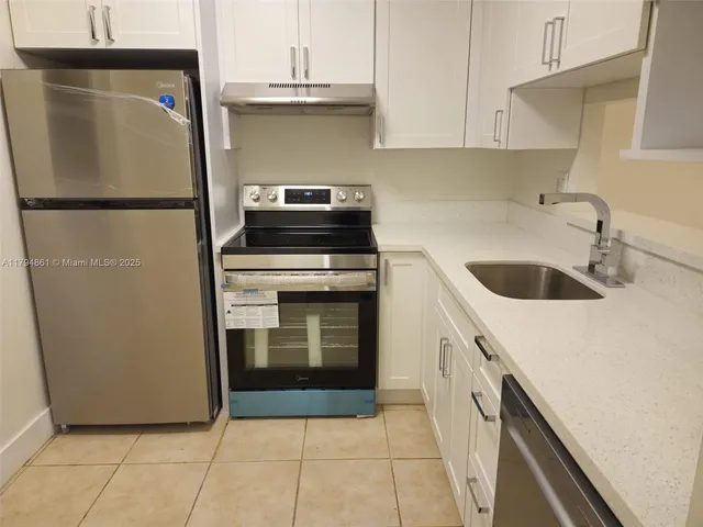 a kitchen with a sink a refrigerator and cabinets