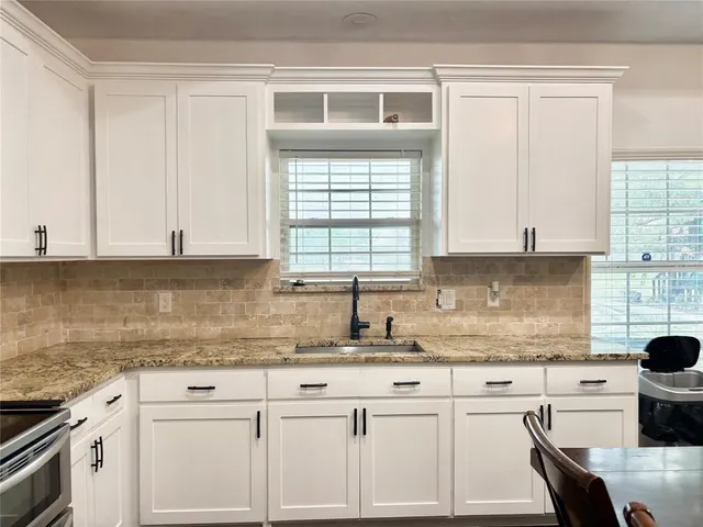 a kitchen with granite countertop white cabinets and white appliances