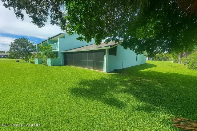 a backyard of a house with plants and large tree