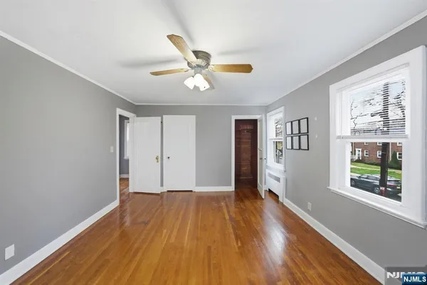 a view of empty room with wooden floor and fan
