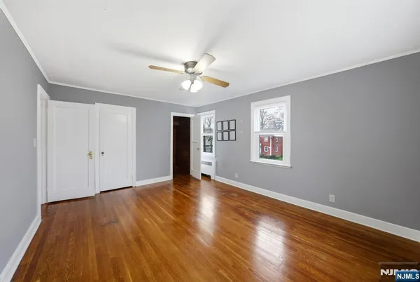 a view of an empty room with window and wooden floor