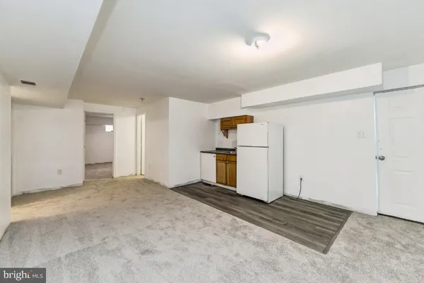 a view of empty room with wooden cabinet and refrigerator
