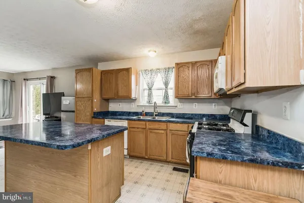 a kitchen with kitchen island granite countertop a sink stove and cabinets