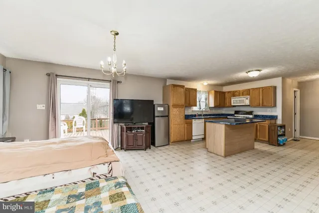 a large kitchen with a refrigerator a stove a sink dishwasher a dining table and chairs with wooden floor