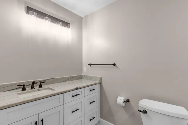 a bathroom with a granite countertop sink a toilet and a mirror
