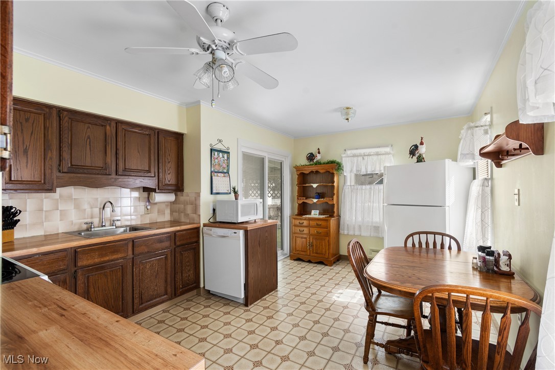 Kitchen featuring backsplash, white appliances, light flooring, a ceiling fan, and butcher block counters