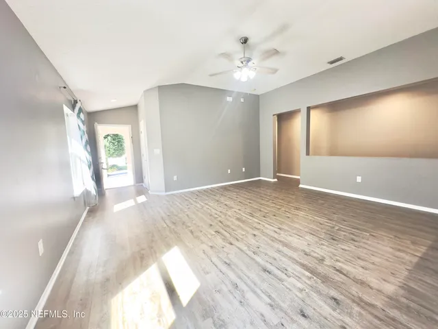 a view of an empty room and chandelier fan