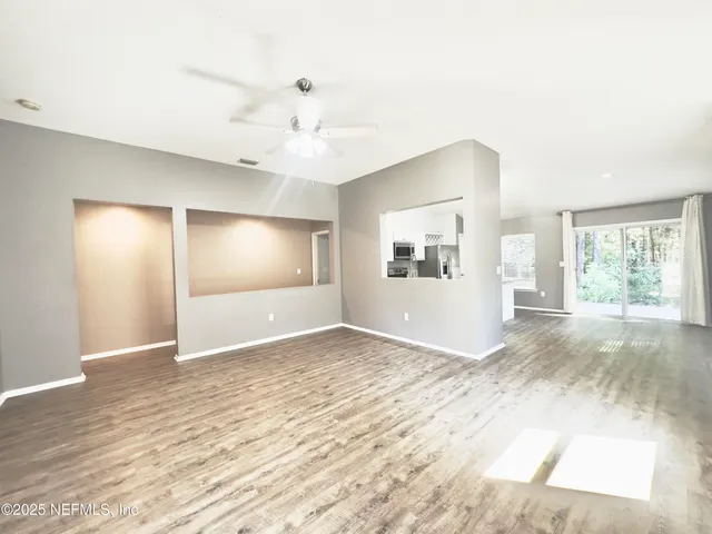 a view of an empty room with window and wooden floor