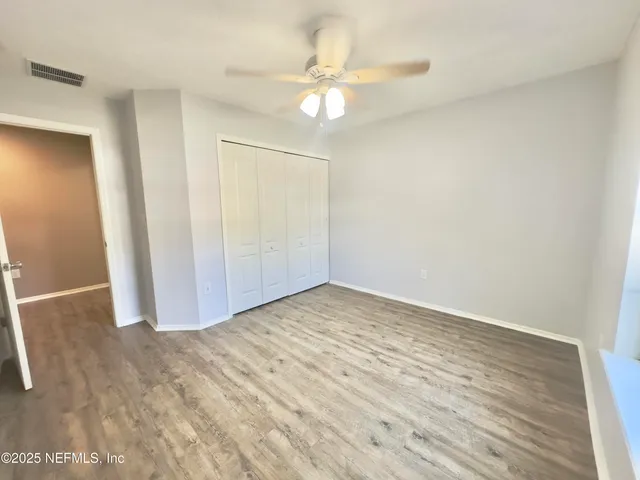 an empty room with wooden floor and fan