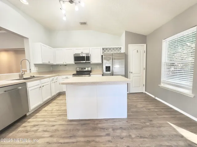 a large kitchen with stainless steel appliances granite countertop a stove a sink a refrigerator a microwave and cabinets