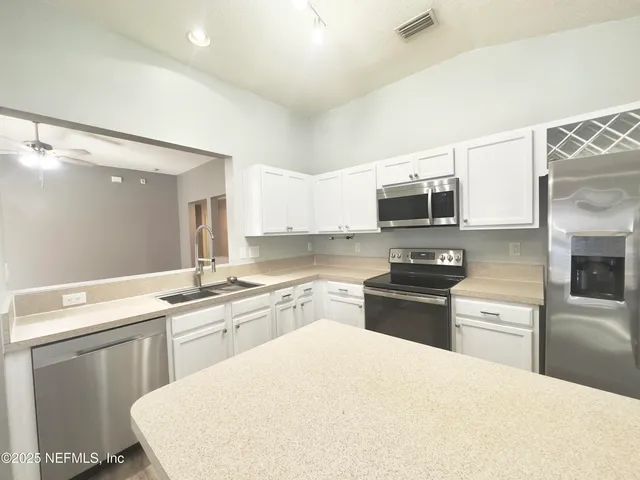 a kitchen with a sink a stove top oven and white cabinets