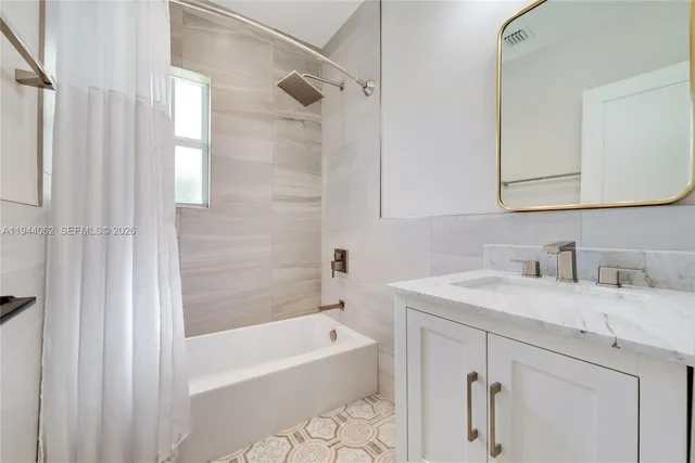 a bathroom with a granite countertop sink a mirror and a bathtub