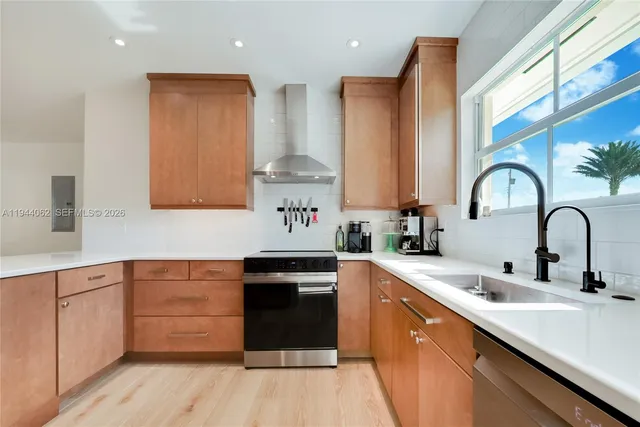 a kitchen with stainless steel appliances granite countertop a sink a stove and cabinets with wooden floor