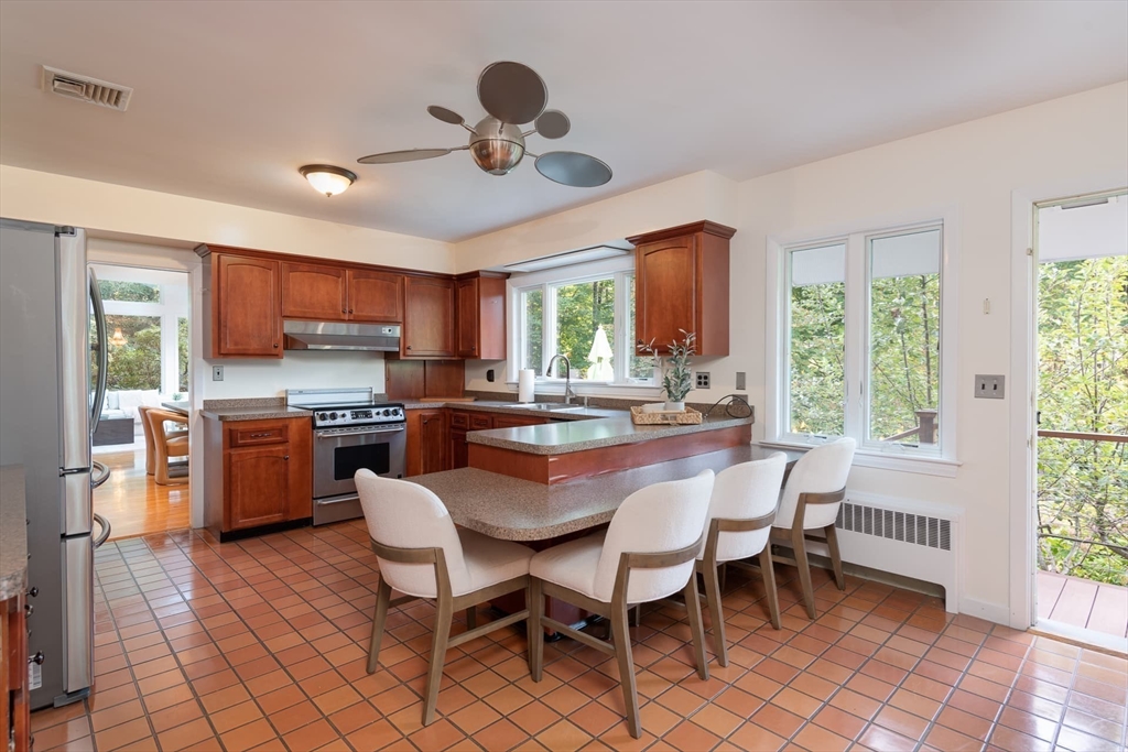 110 Robin Road Weston, MA 02493 - Photo 12 of 40 a dining area with stainless steel appliances a table chairs and a refrigerator
