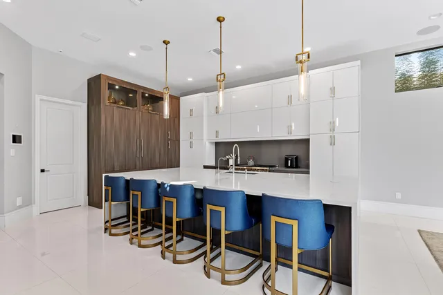 a kitchen with kitchen island granite countertop a table chairs a sink dishwasher and cabinets