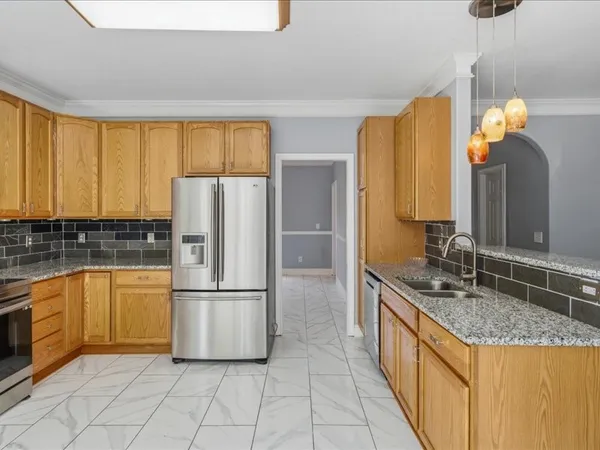 a kitchen with granite countertop a refrigerator a stove and white cabinets