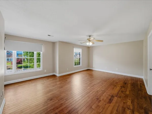 an empty room with wooden floor and windows