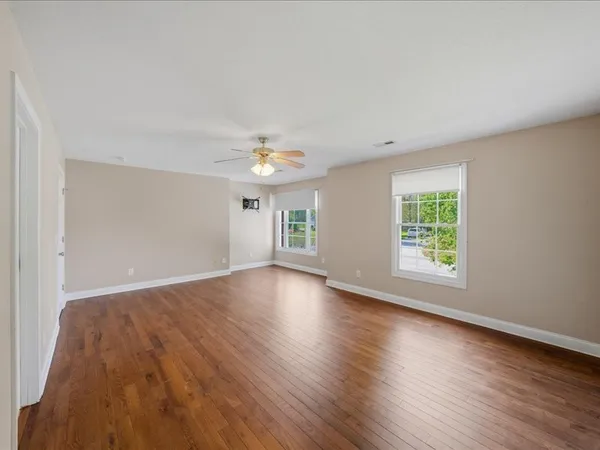 an empty room with wooden floor and windows