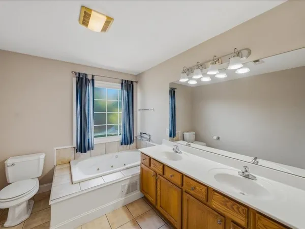 a spacious bathroom with a double vanity sink a toilet and a large mirror