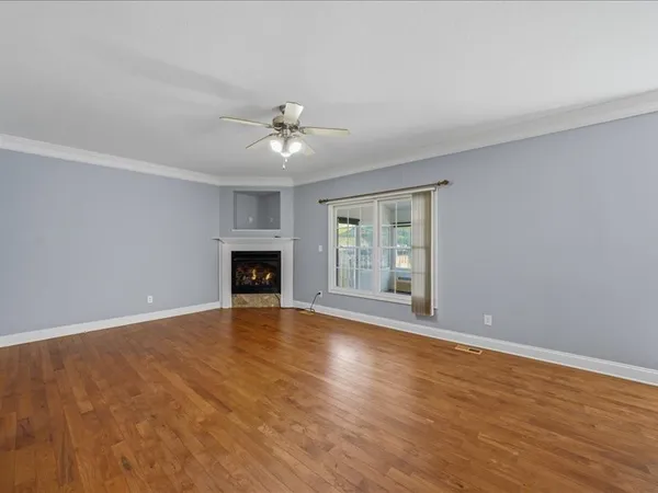 a view of an empty room with wooden floor and a window