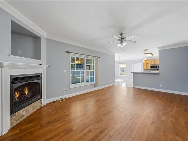 a view of an empty room with wooden floor fireplace and a window