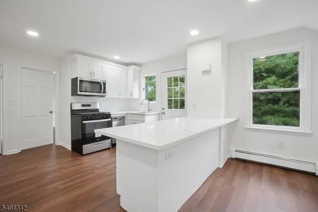 a kitchen with stainless steel appliances white cabinets a stove a microwave and a refrigerator