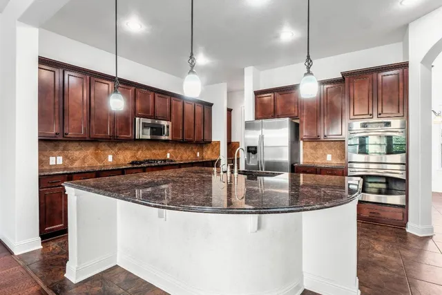 a kitchen with stainless steel appliances granite countertop a sink refrigerator and cabinets