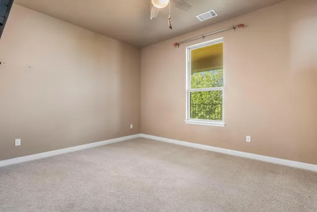 an empty room with a window and a ceiling fan